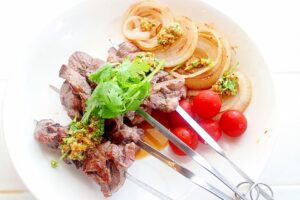 パクチーの特製タレで食べるラム肉の串焼き